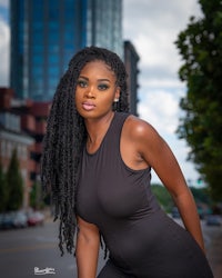 a young black woman in a black dress posing for a photo